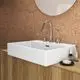 Weißer Waschtisch mit rechteckiger Form und senkrechtem Waschbecken. Ideal Standard Armaturen sind aus glänzendem Metall. Holzoberfläche im Hintergrund. Seifenspender und Rasierpinsel neben dem Becken.